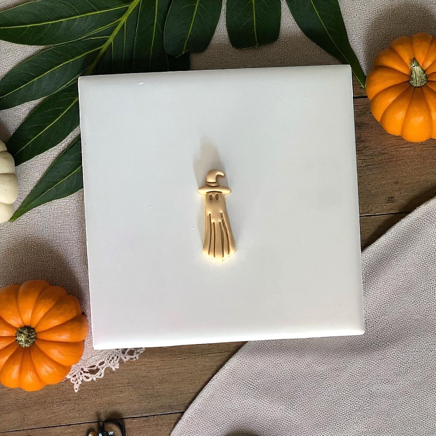 Golden ghost clay charm with witch hat on white tile