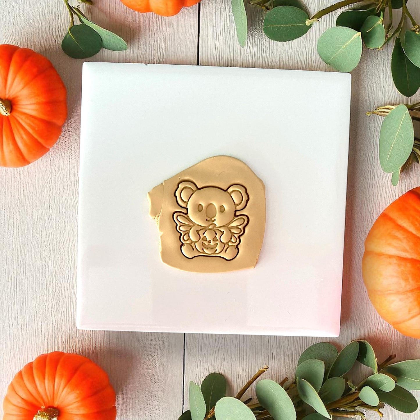 Golden clay impression of koala holding pumpkin