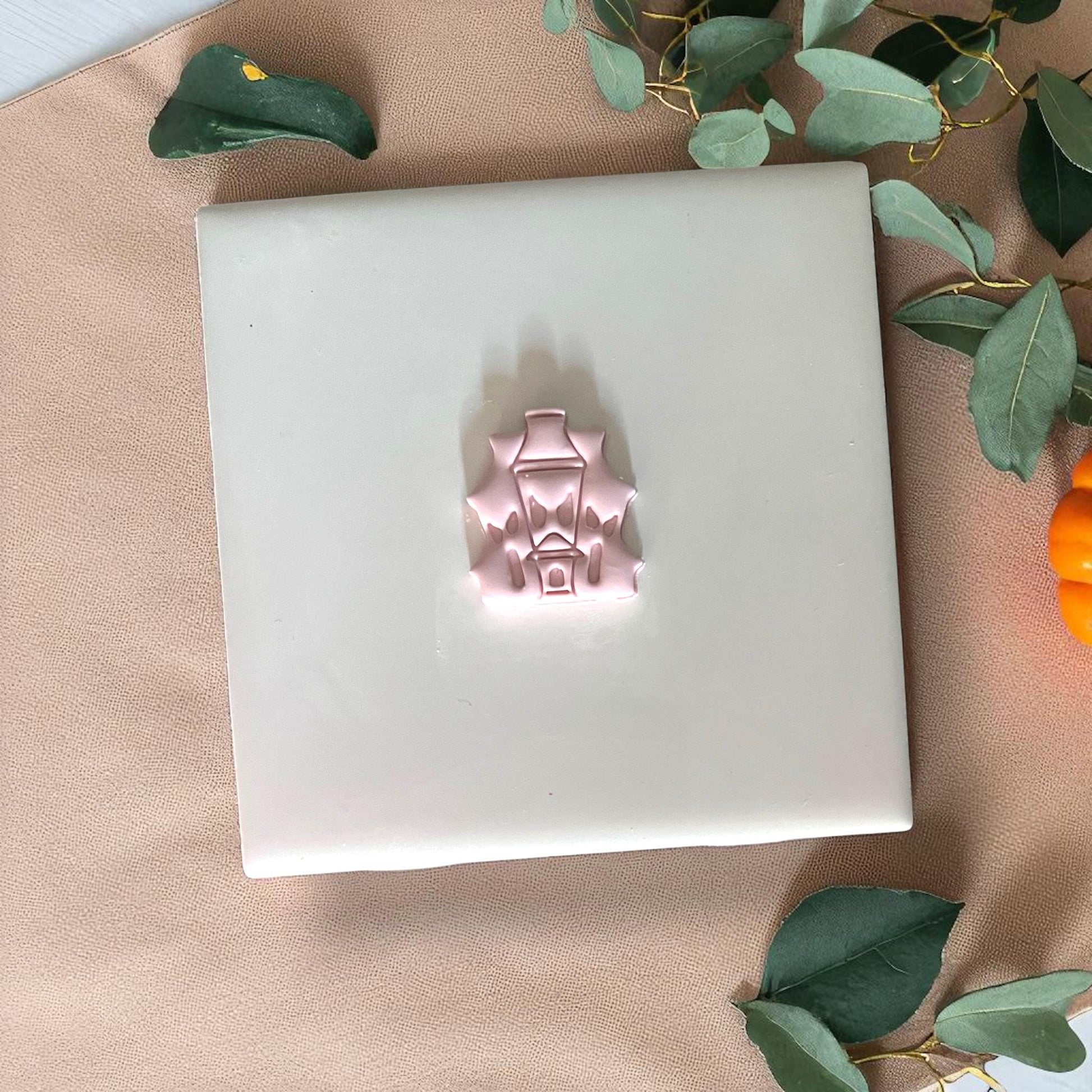 Pink haunted house clay piece on white tile