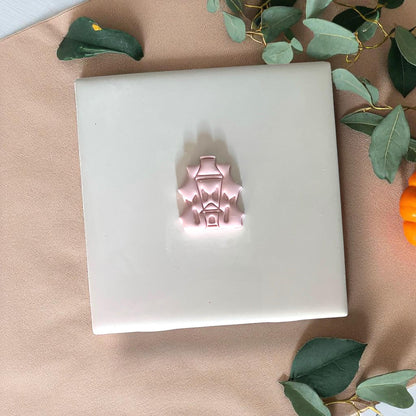 Pink haunted house clay piece on white tile
