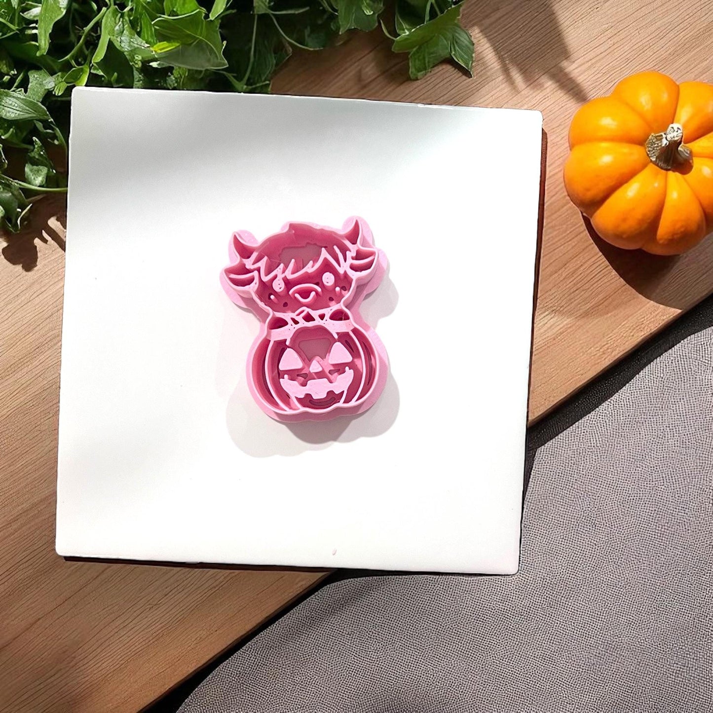 Pink highland cow pumpkin clay cutter on tile