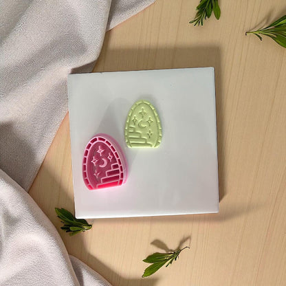 Green clay imprint and pink cutter shaped like an arched doorway with moon, stars, and staircase.