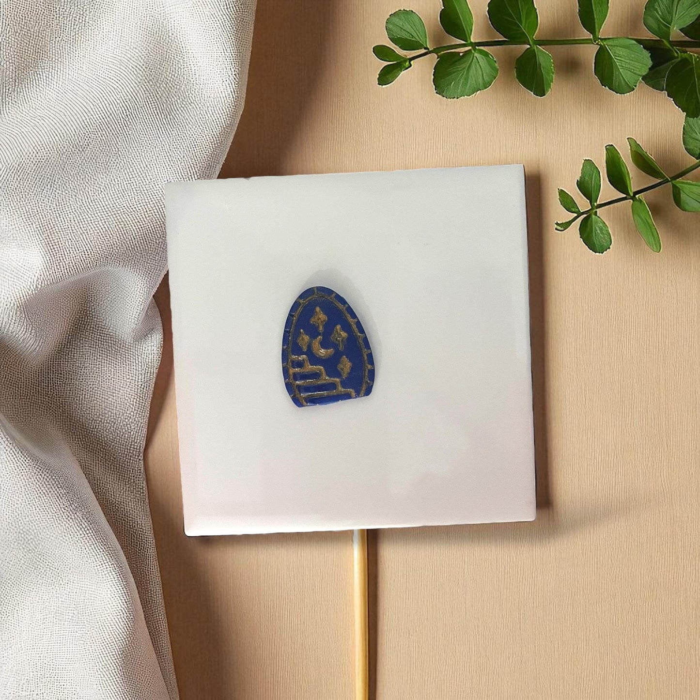 Blue clay imprint shaped like arched doorway with staircase, moon, and stars on white tile.