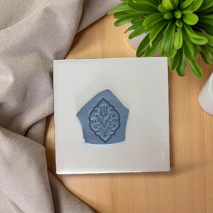 Gray tulip floral clay impression on white tile with greenery