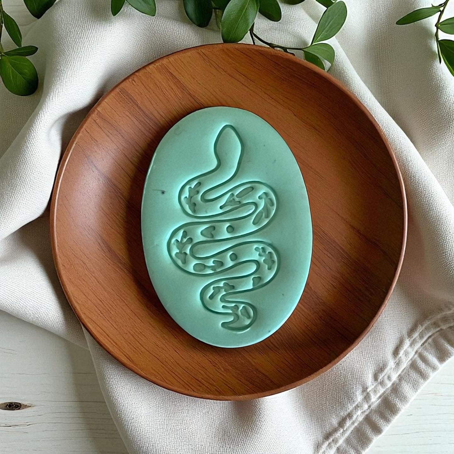 Large teal snake clay design on wood plate