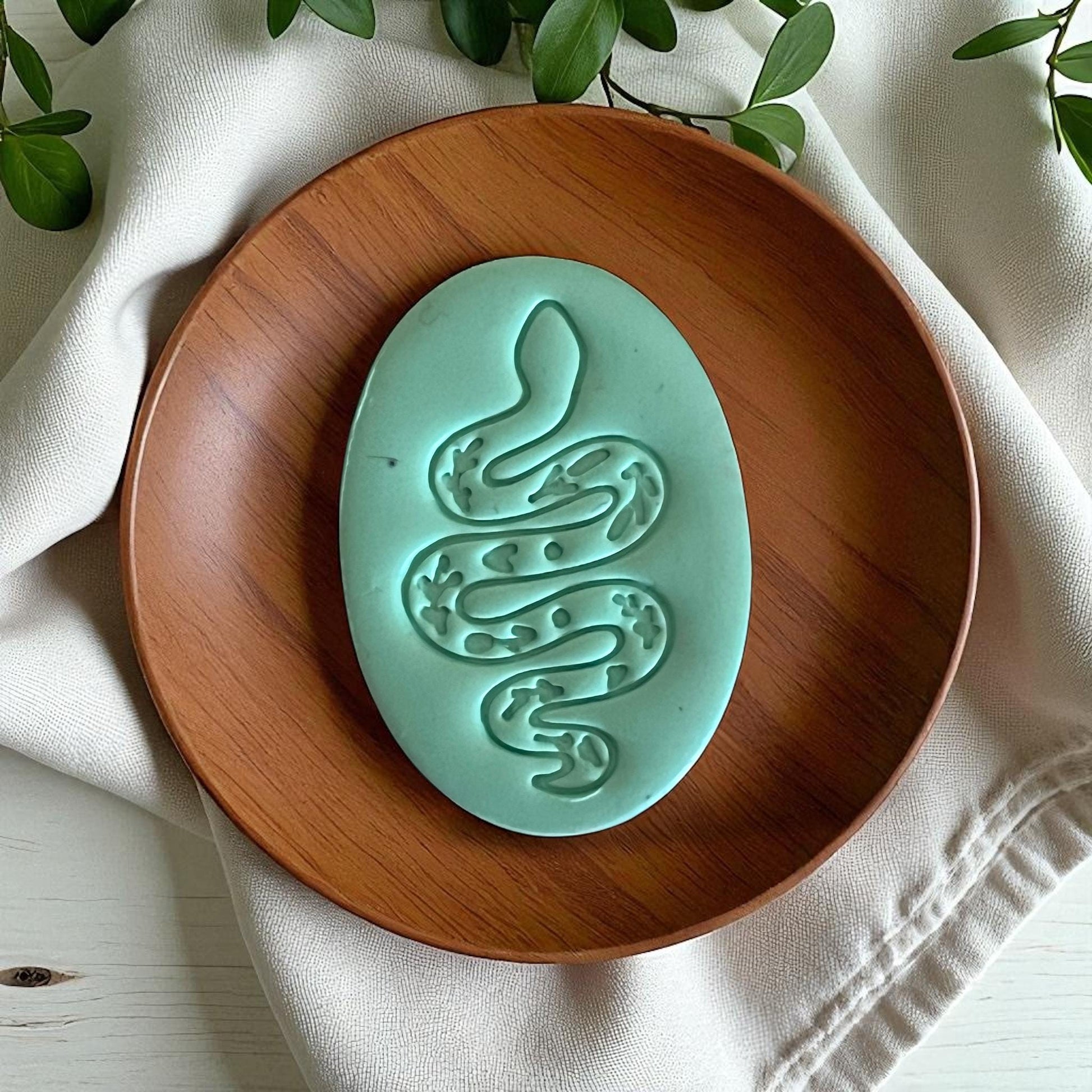 Large teal snake clay design on wood plate