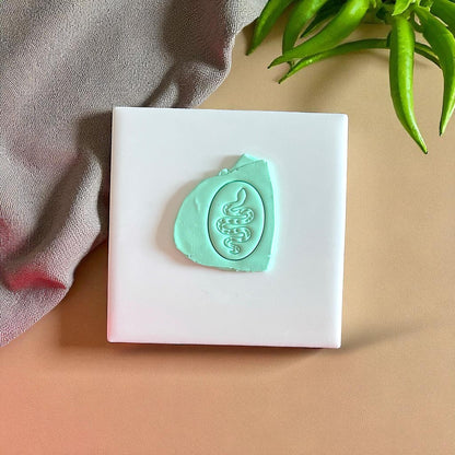 Teal snake clay impression on white tile