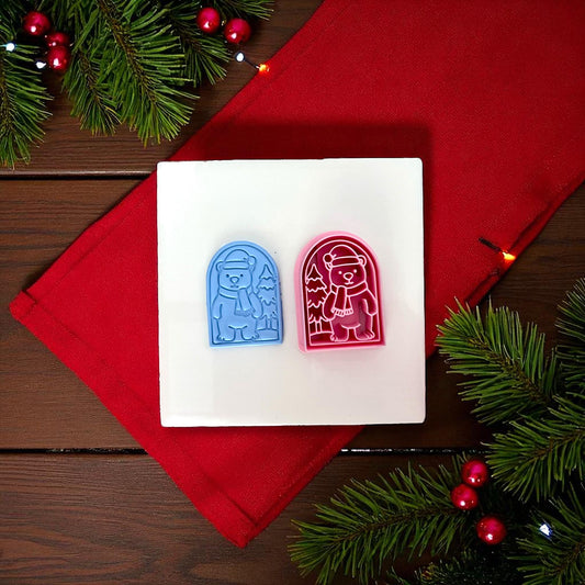 Blue polar bear clay imprint displayed on white plate with red cloth and pine branches.