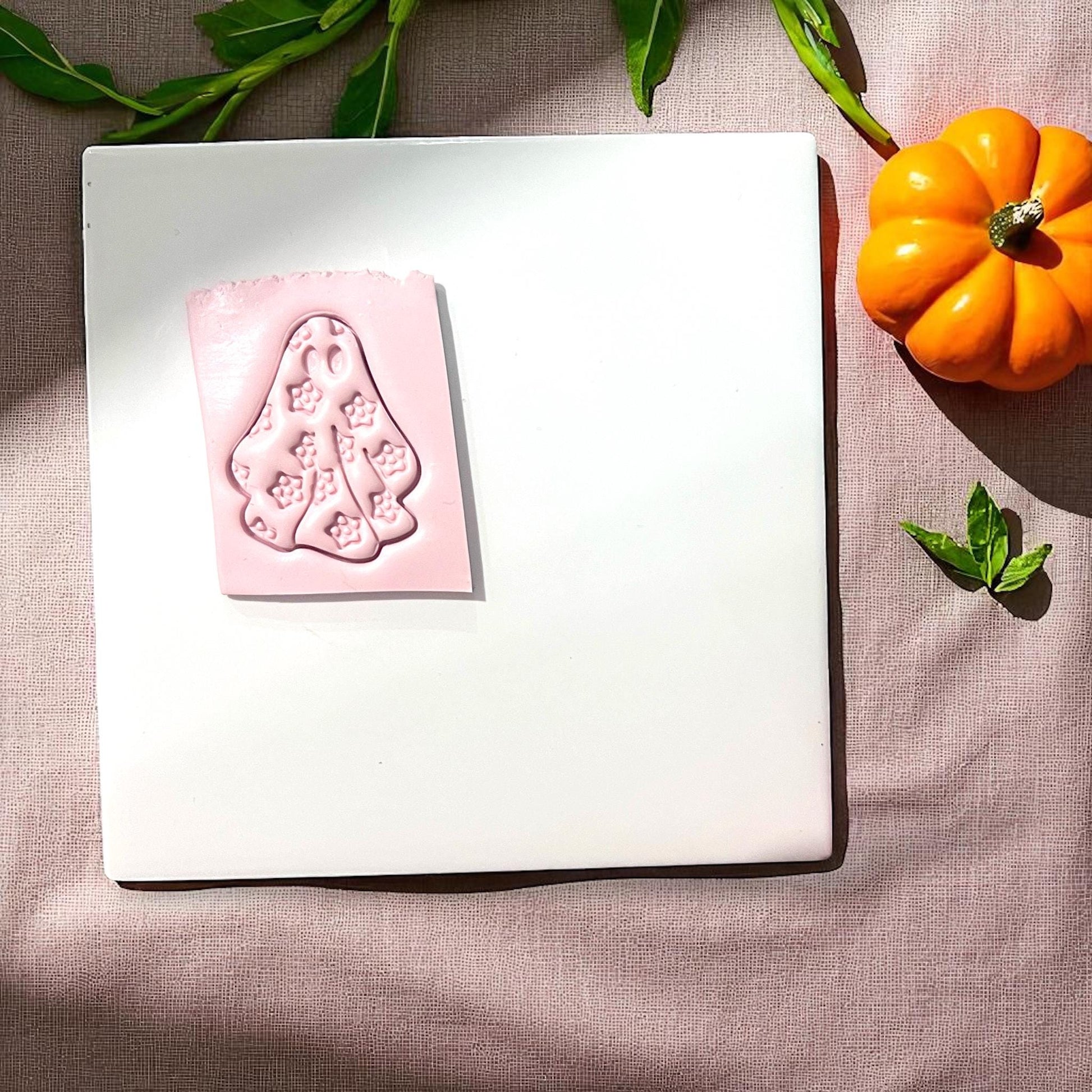 Pink floral ghost clay impression on white tile with pumpkins