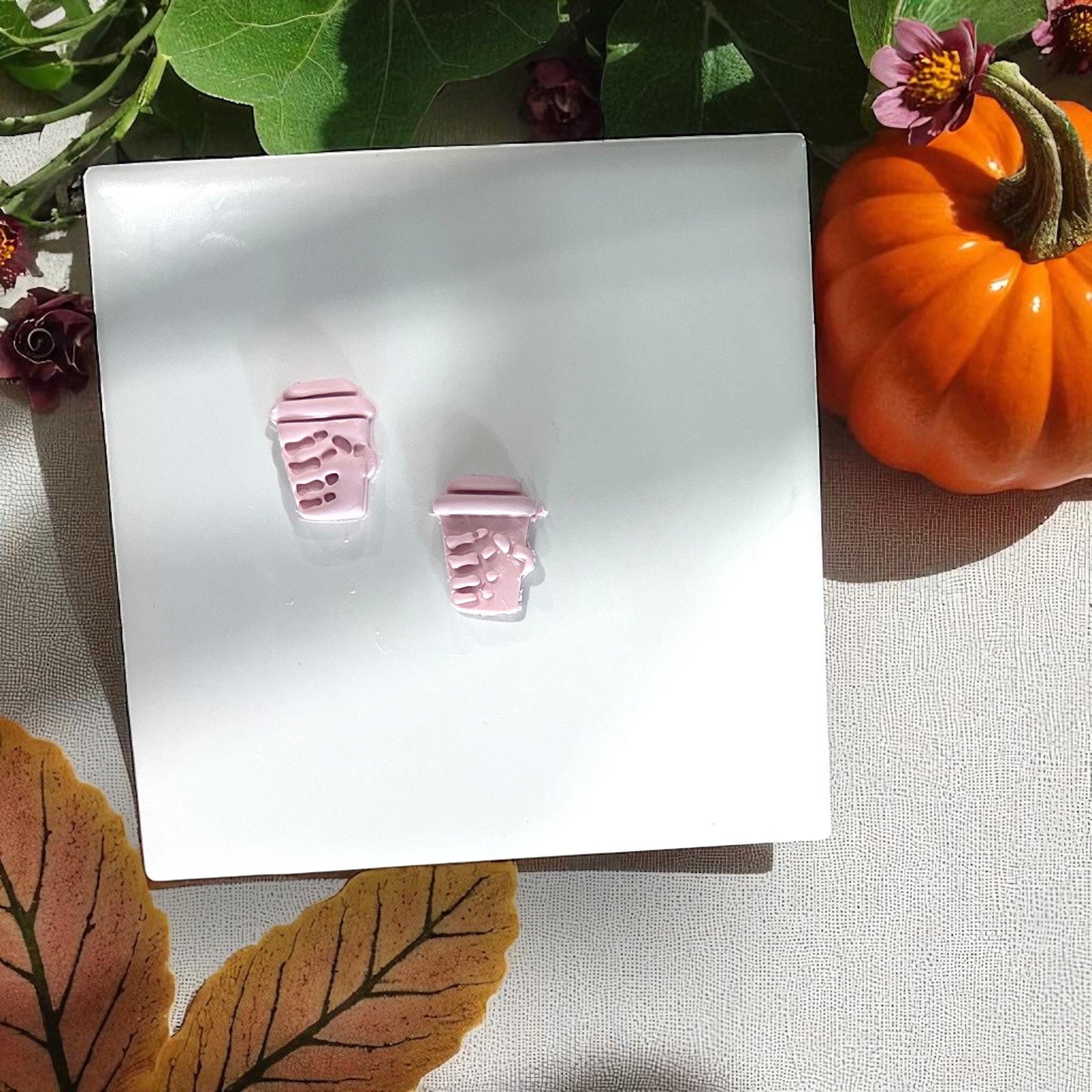 Small pink clay skeleton coffee cups on white tile with pumpkin