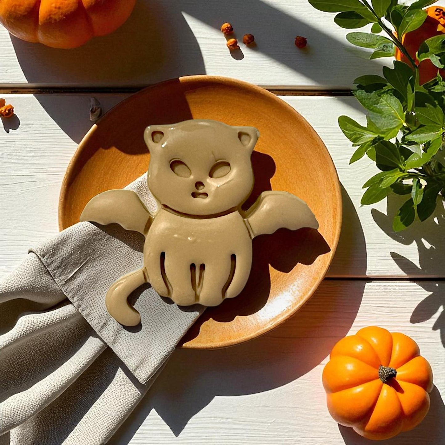 Large clay vampire kitten with bat wings on plate with pumpkins