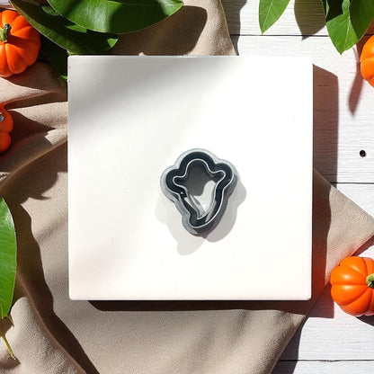 Thin ghost silhouette clay cutter on white tile with pumpkins
