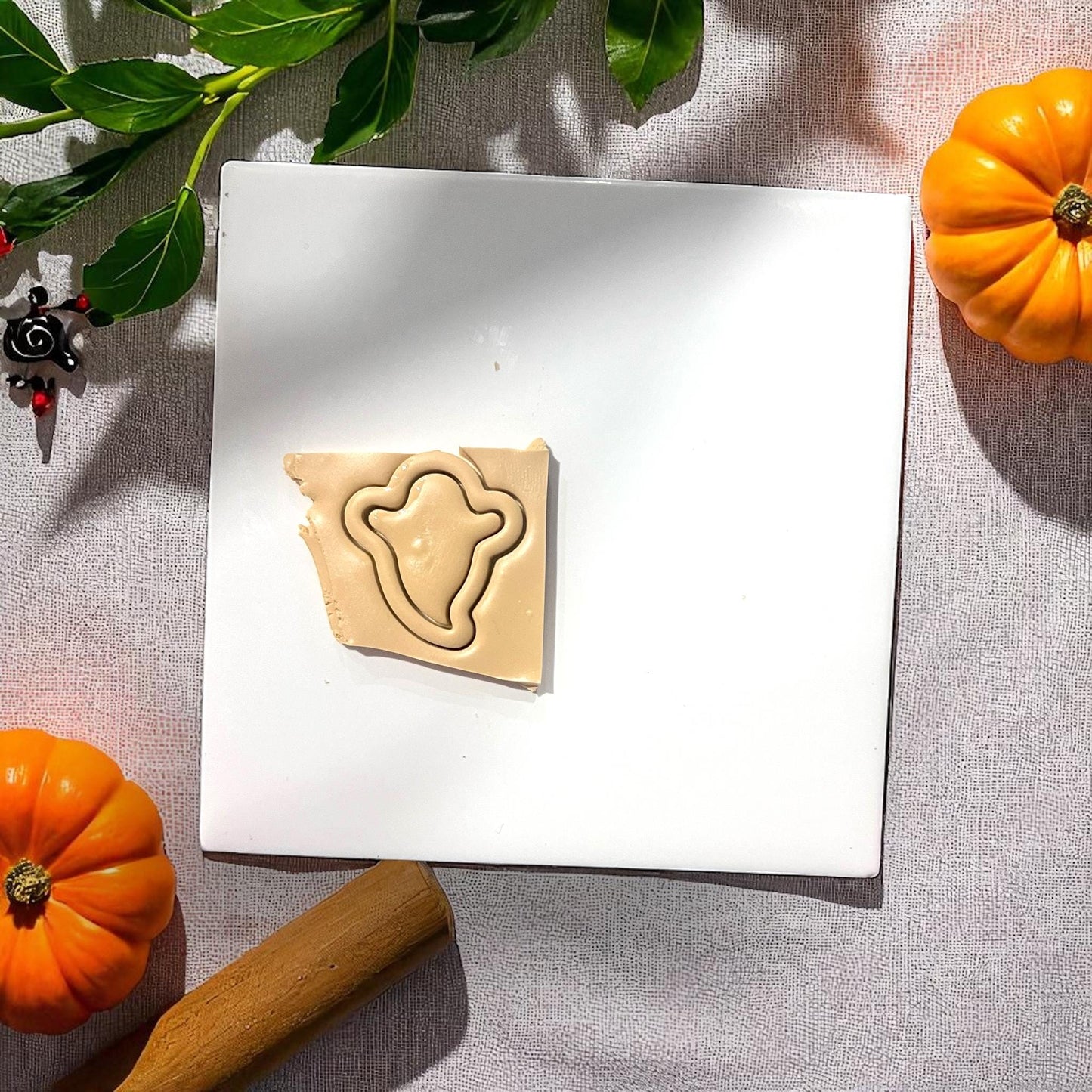 Thin ghost clay cutter impression in slab of beige clay with pumpkins