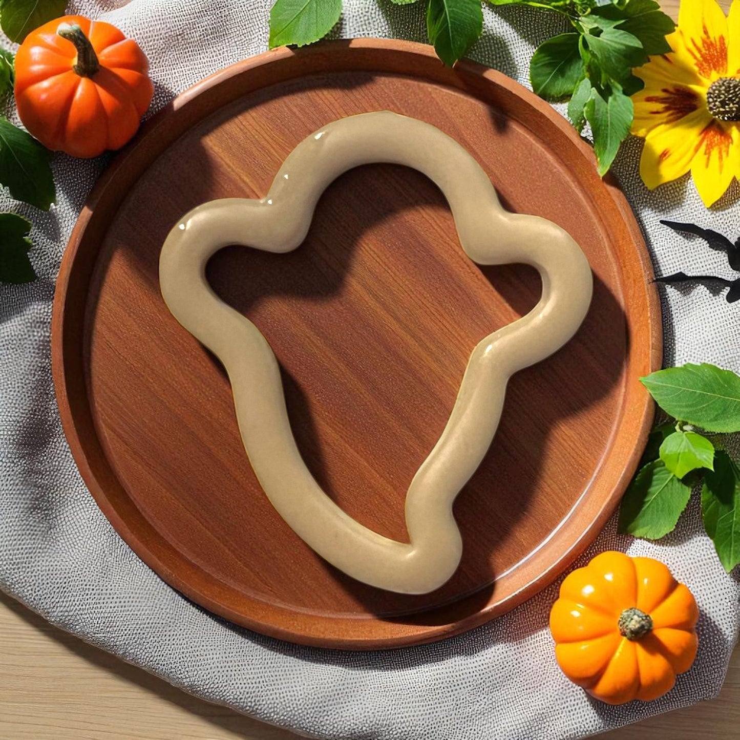Large thin ghost silhouette clay piece on wooden plate with pumpkins