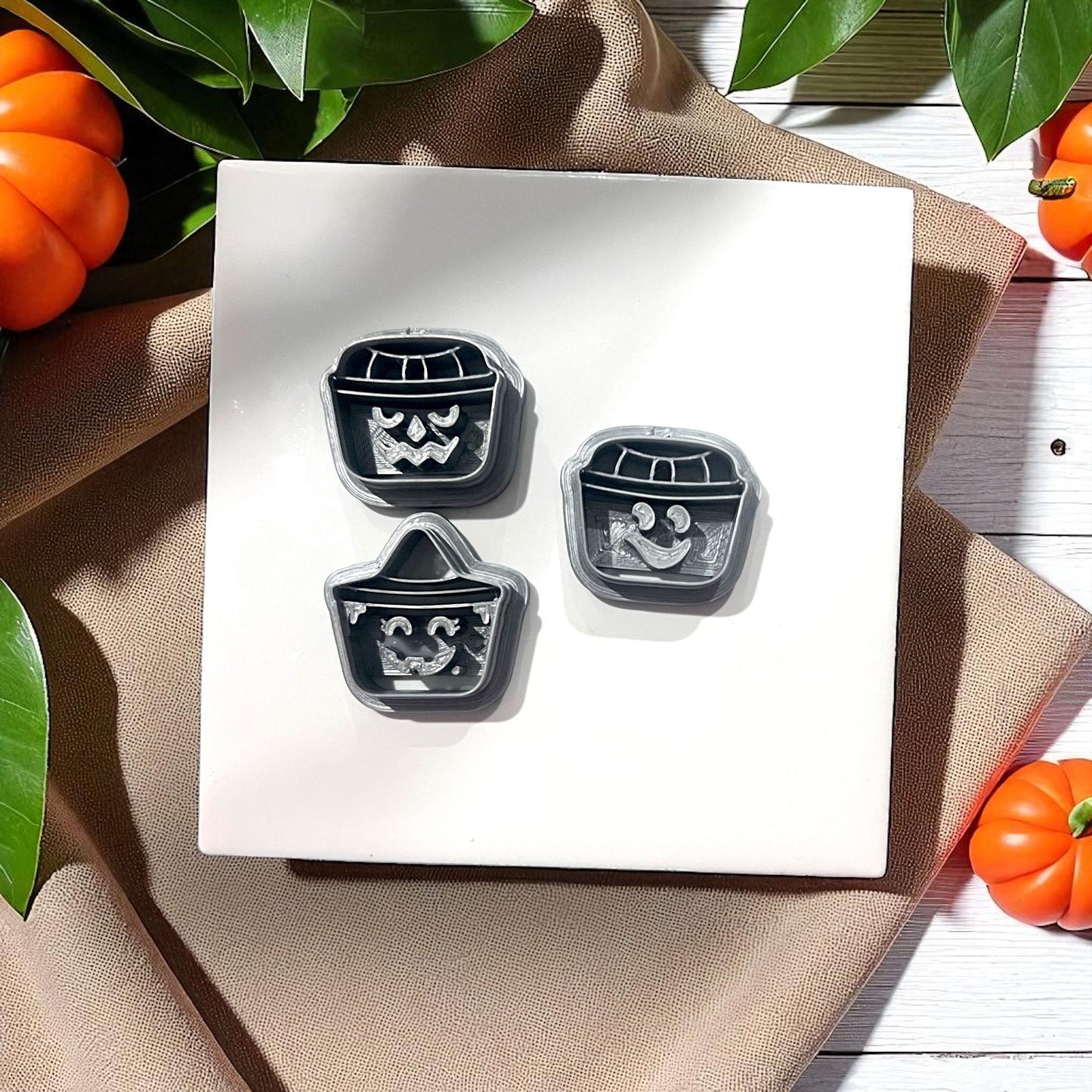 Three pumpkin bucket face clay cutters on white tile