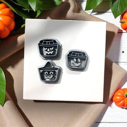 Three pumpkin bucket face clay cutters on white tile