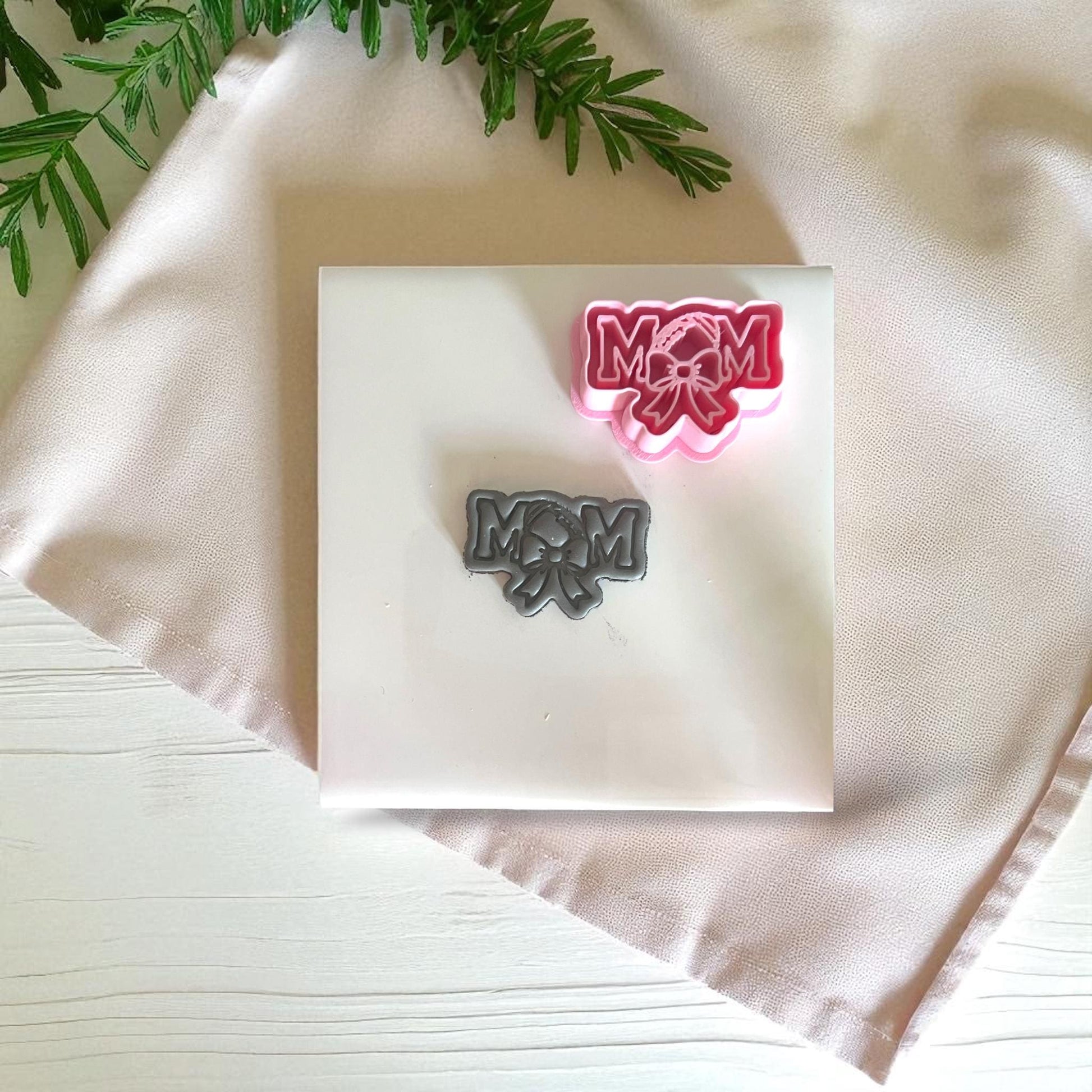 Pink football mom cutter with black clay piece on white tile