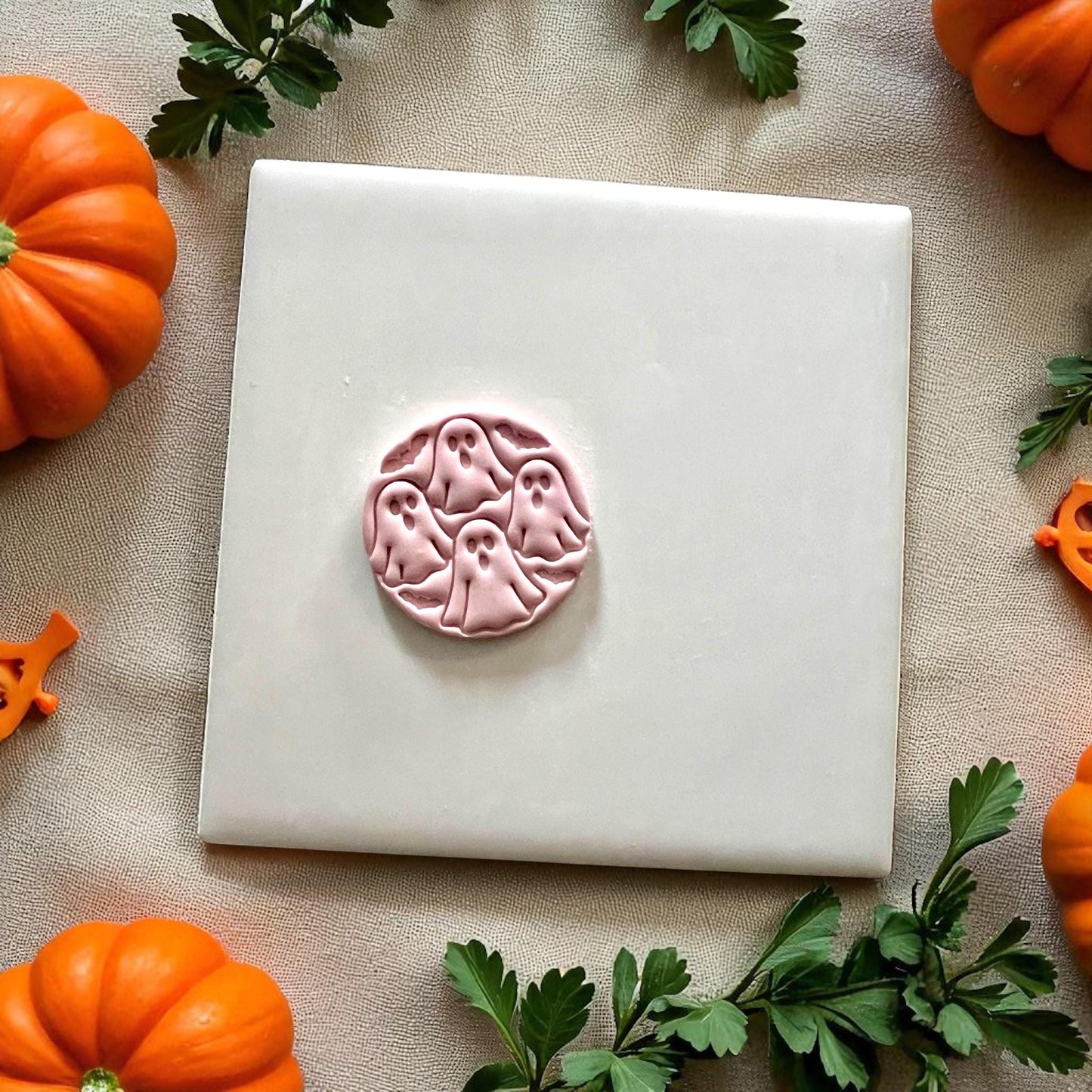 Pink clay ghost circle design on white tile with pumpkins