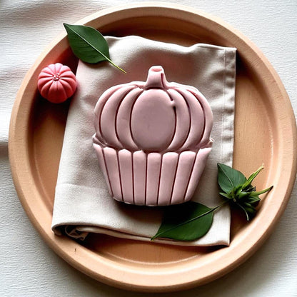 Large pumpkin cupcake clay piece on cloth napkin with greenery