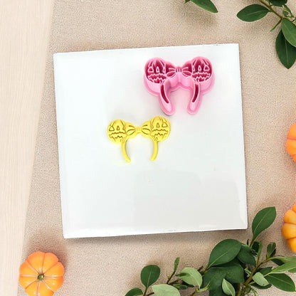 Pink pumpkin ears cutter with yellow clay imprint on white tile.