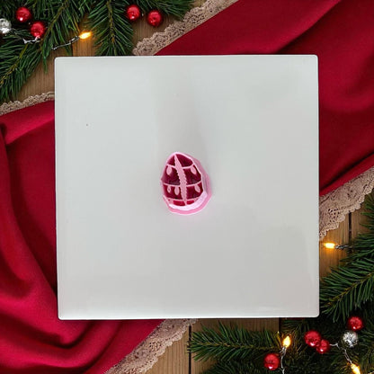Pink cowrie shell Christmas lights clay cutter on white tile with red fabric.