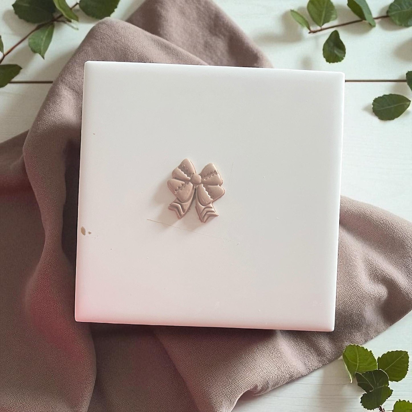 Small clay imprint of a football bow design