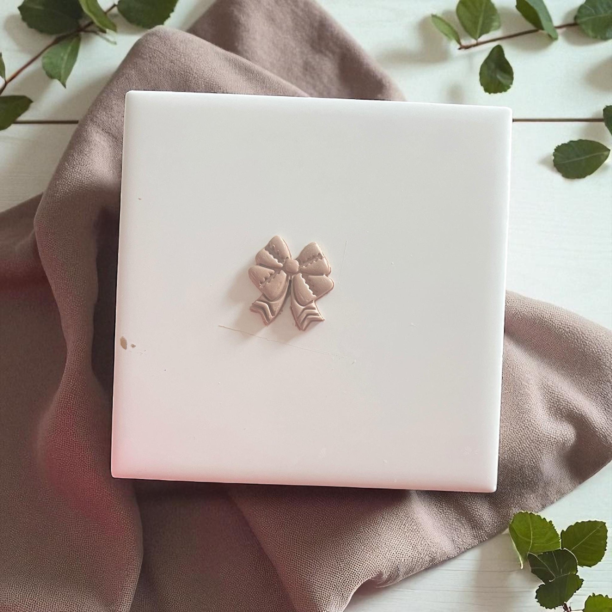 Small clay imprint of a football bow design