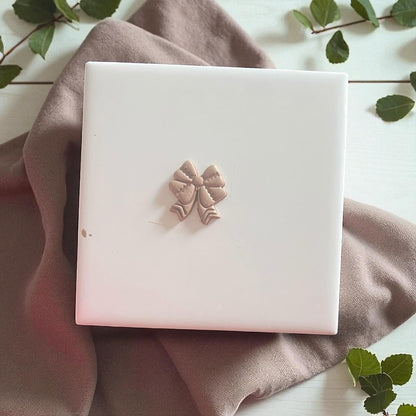 Small clay imprint of a football bow design