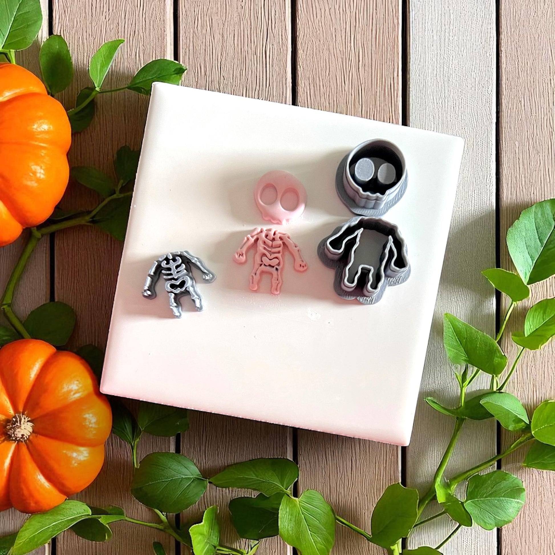 Skeleton clay impressions and cutters on white tile with pumpkins