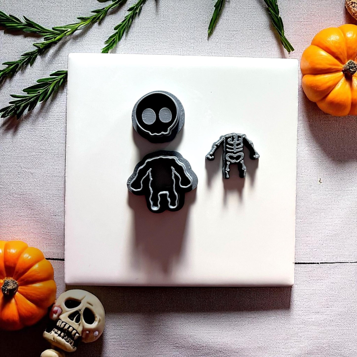 Black skeleton clay cutters on white tile with pumpkins