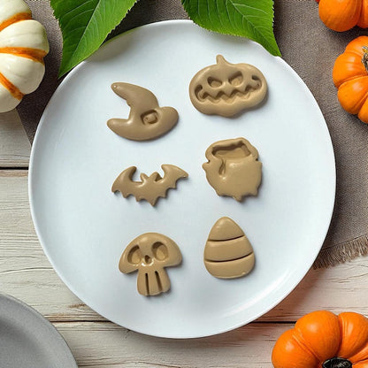 Brown clay Halloween shapes on white plate with leaves and pumpkins