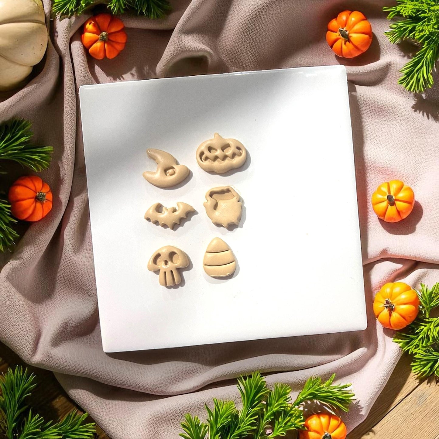 Halloween clay shapes on white tile with mini pumpkins