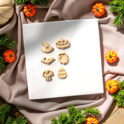 Halloween clay shapes on white tile with mini pumpkins