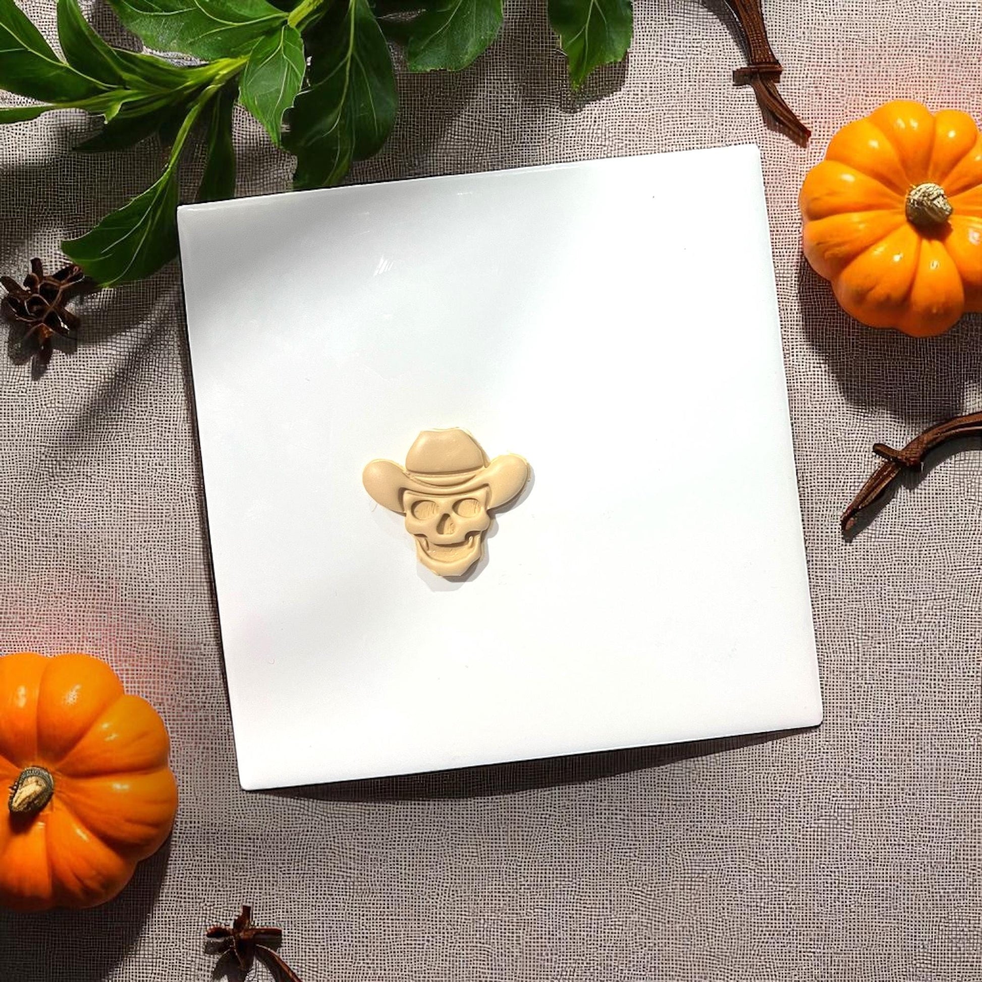 Cowboy skull clay shape on white tile with pumpkins