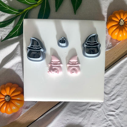 Witch hat house cutters and clay pieces on white tile with pumpkins