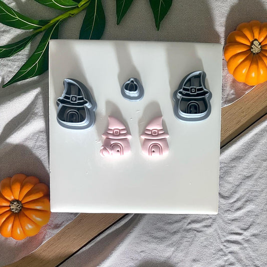 Witch hat house cutters and clay pieces on white tile with pumpkins