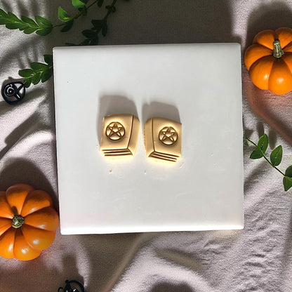 Two clay spellbook designs with pentagram on white tile