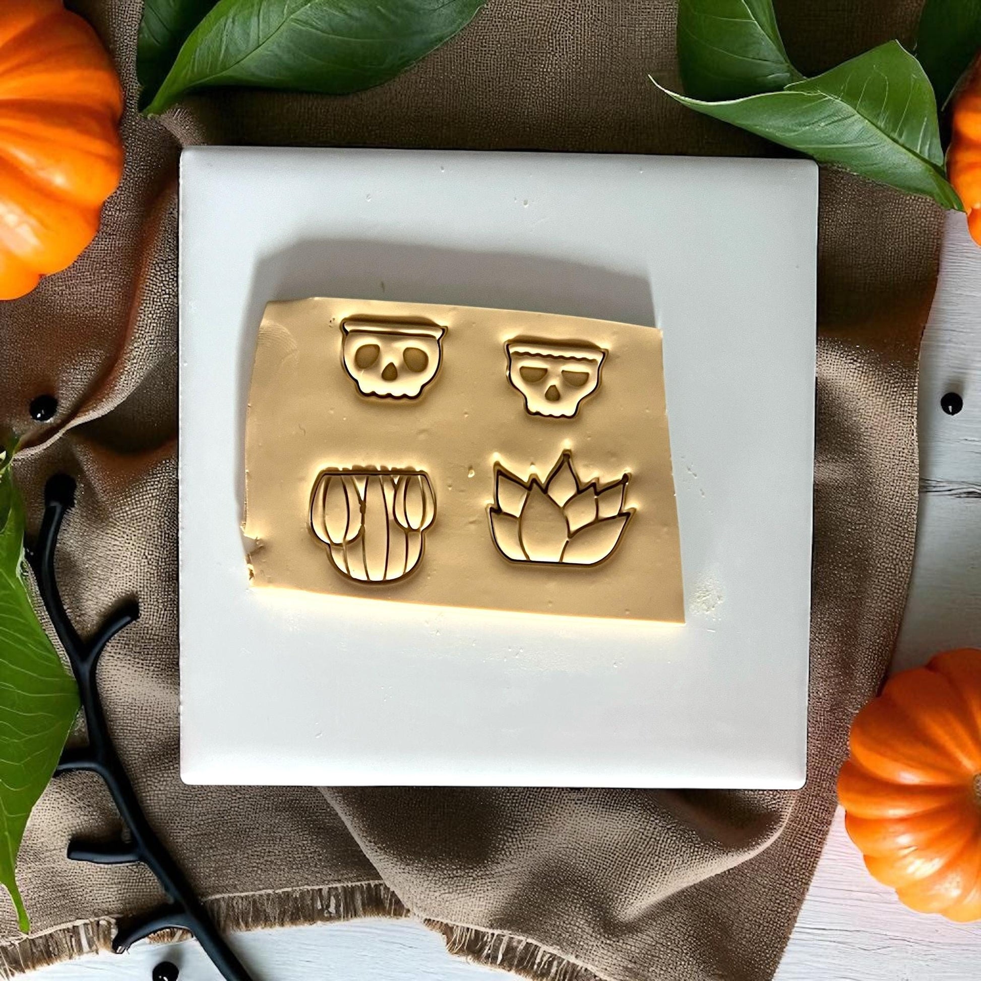 Two skull planter clay designs on white tile with pumpkins