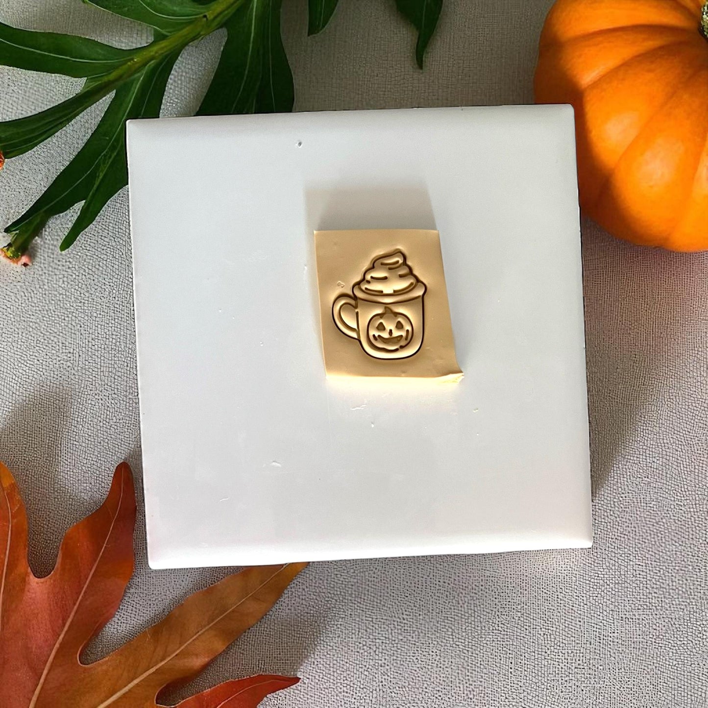 Pink pumpkin latte mug clay cutter on white tile with pumpkins