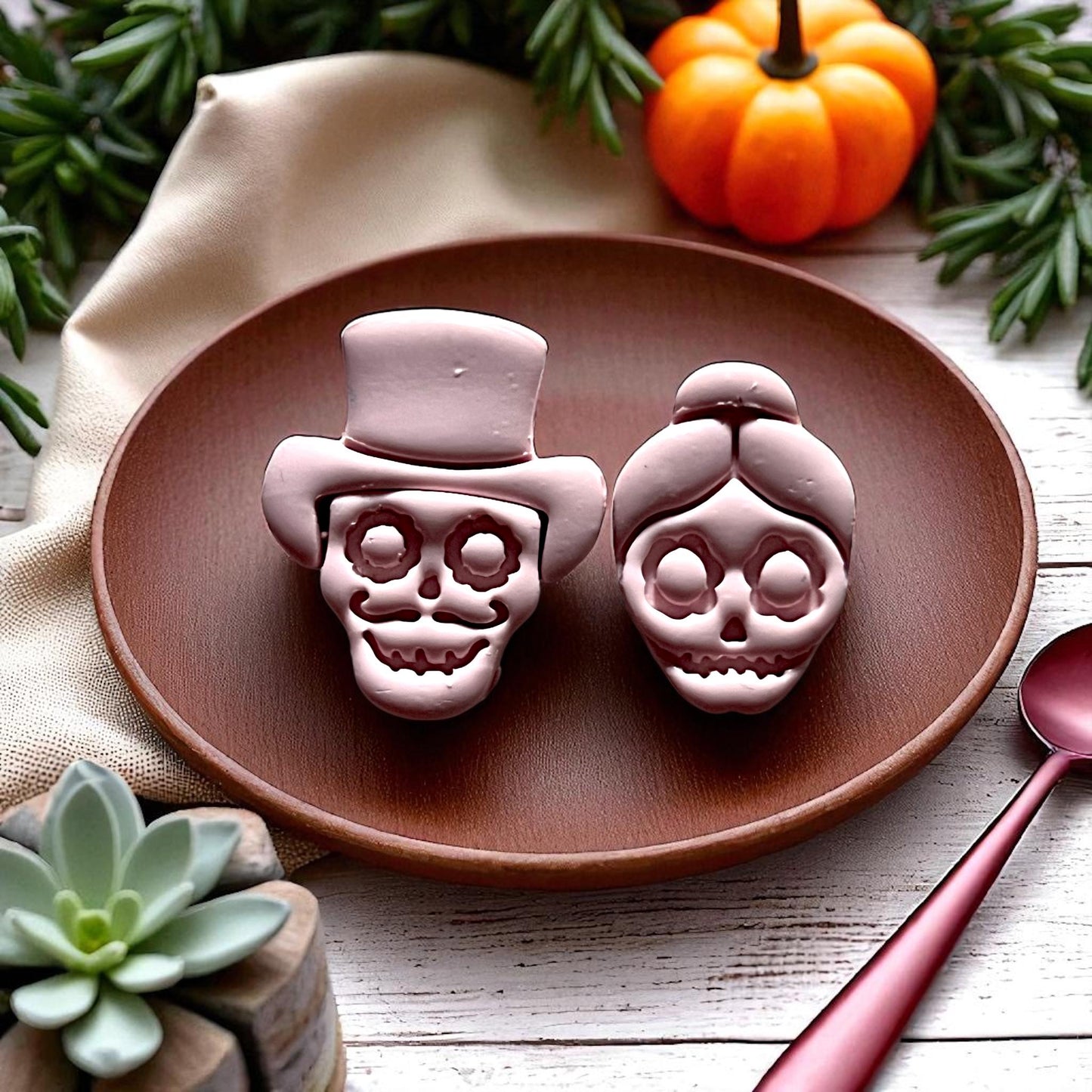 Bride and groom skull clay designs on round wooden plate with fall décor