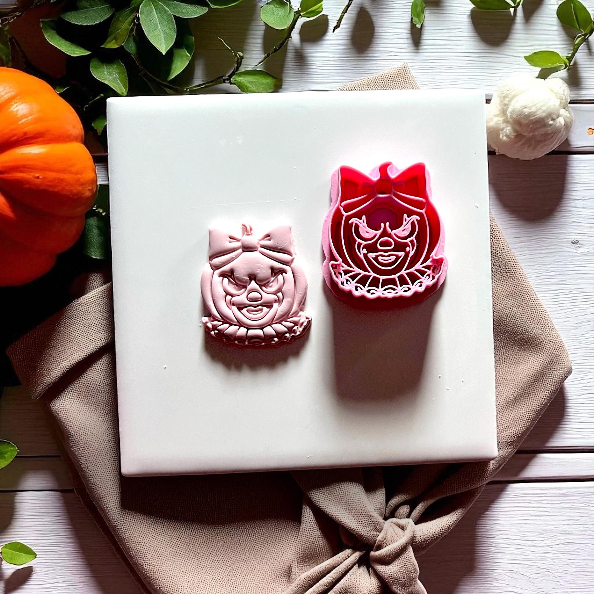 Clown pumpkin face with bow cutter and pink clay imprint side by side
