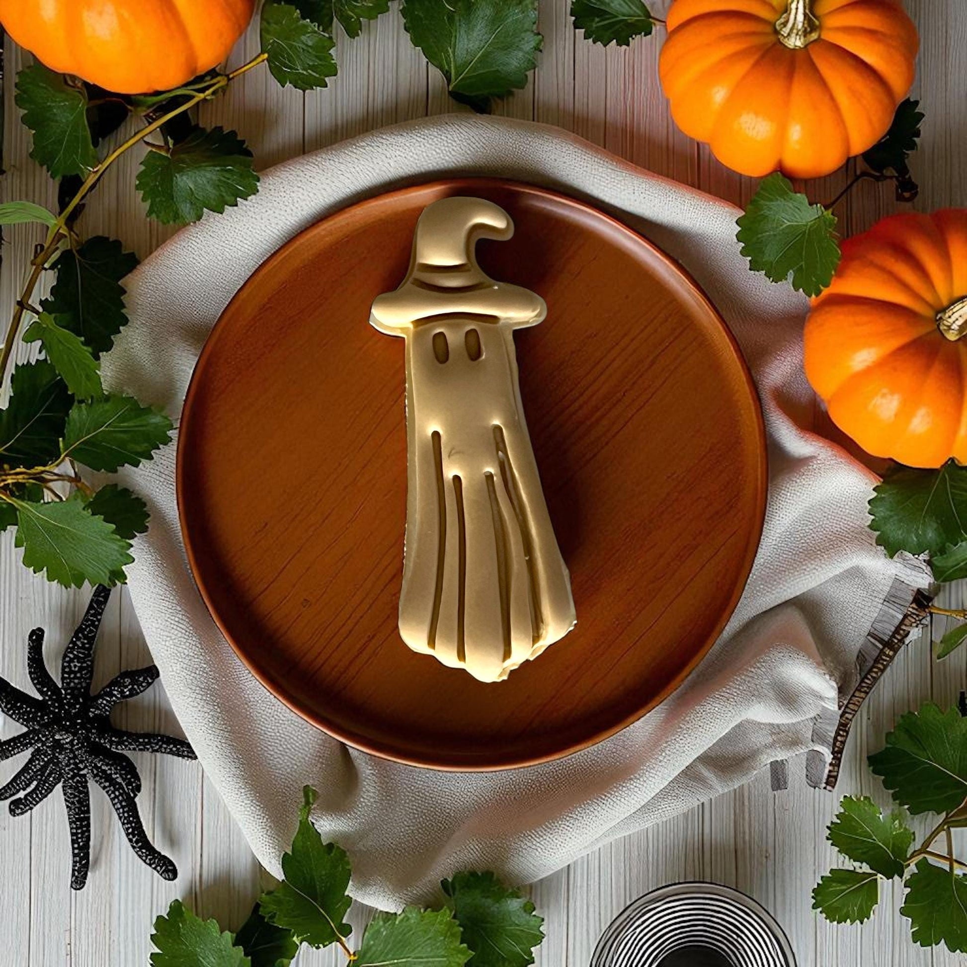 Golden ghost clay piece with witch hat on wooden plate
