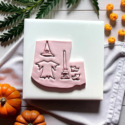 Full witch cutter impression with broom hat dress and shoes on clay slab