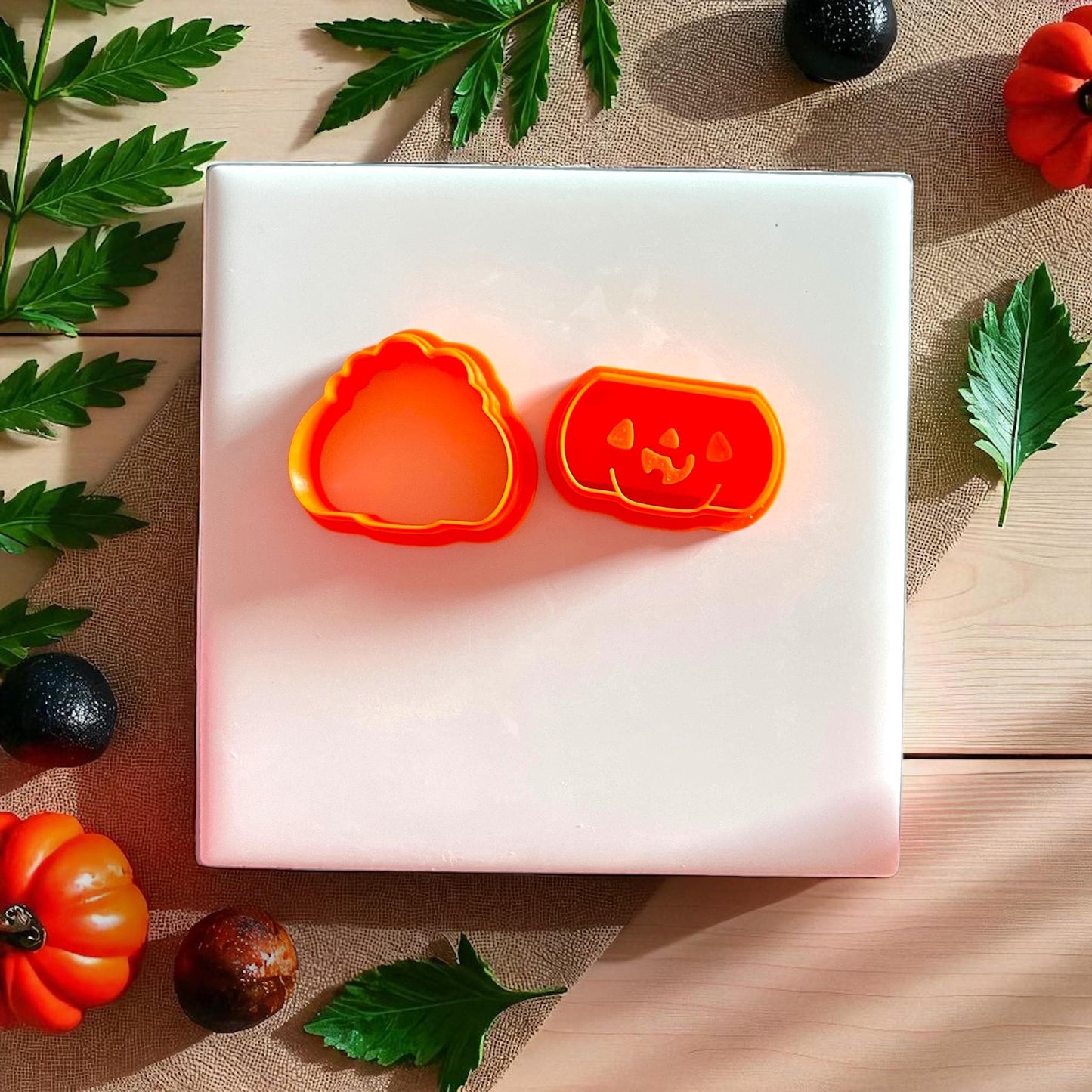 Orange pumpkin clay cutters with jack o lantern face on white tile