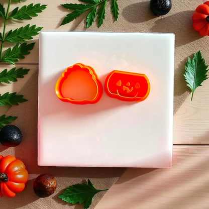 Orange pumpkin clay cutters with jack o lantern face on white tile