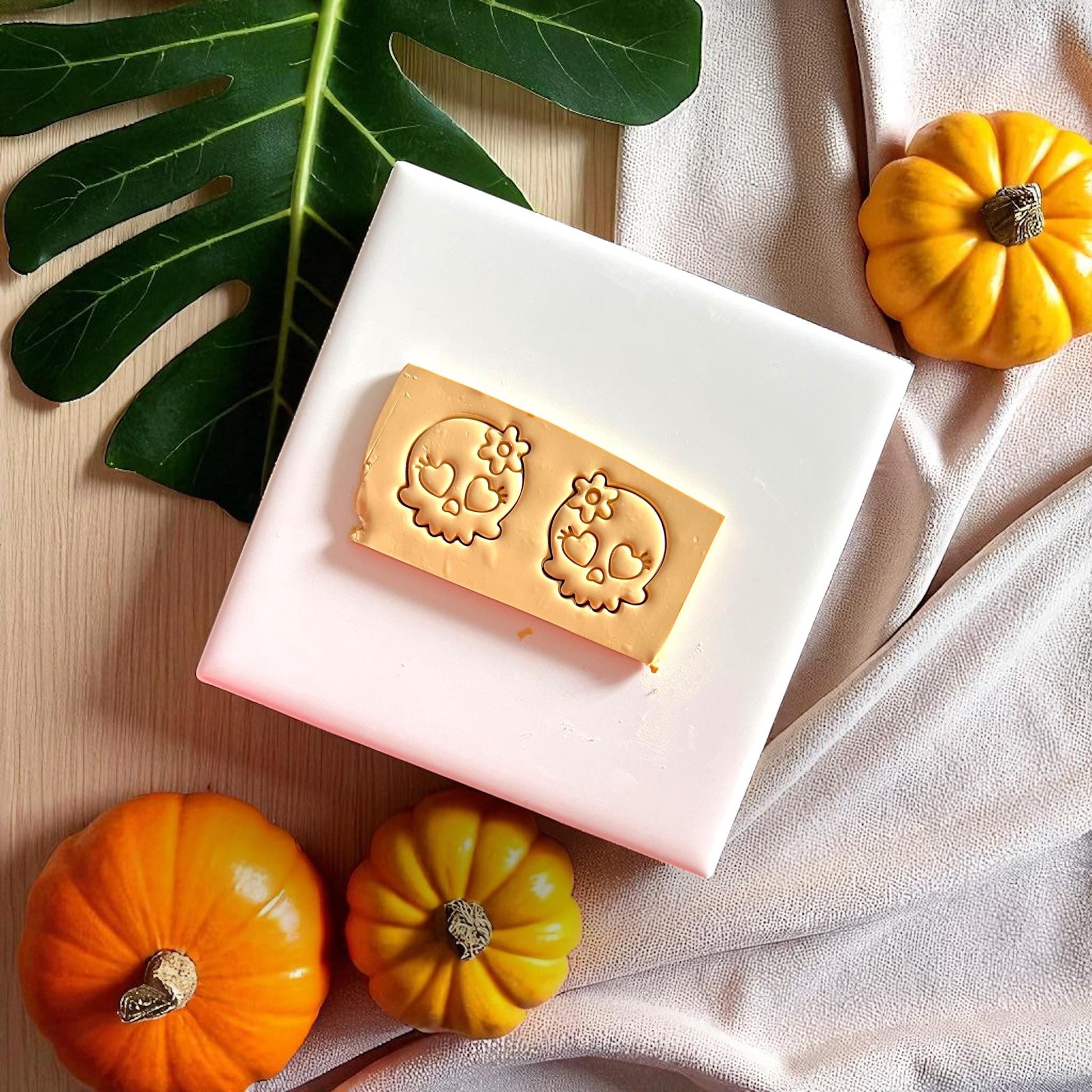 Golden clay skull imprints with heart eyes and flower design on white tile