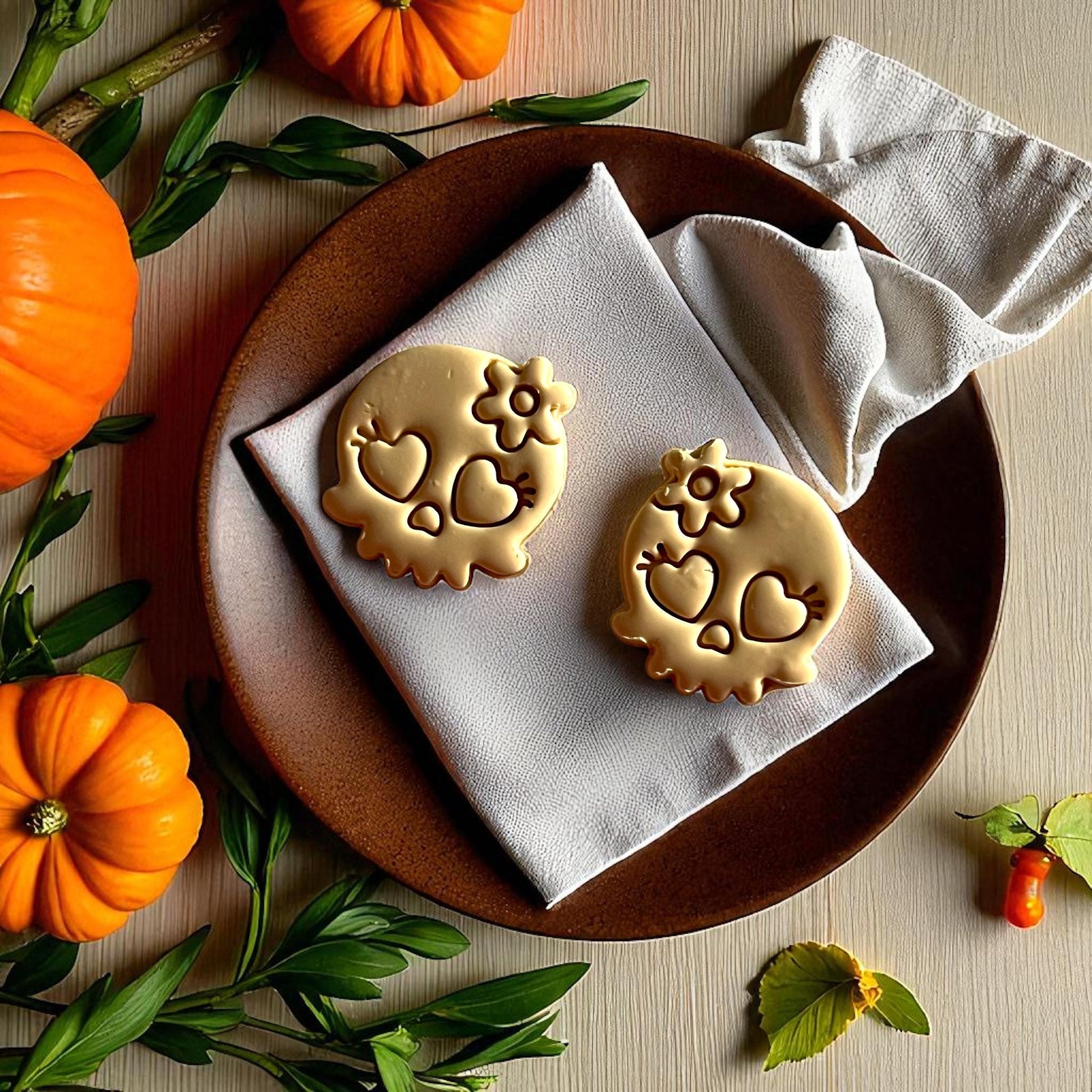 Large golden skull clay cutouts with heart eyes and flower on brown plate
