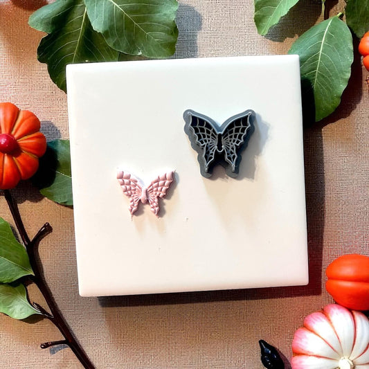Spiderweb butterfly clay cutter and clay impression on white tile with leaves and pumpkins