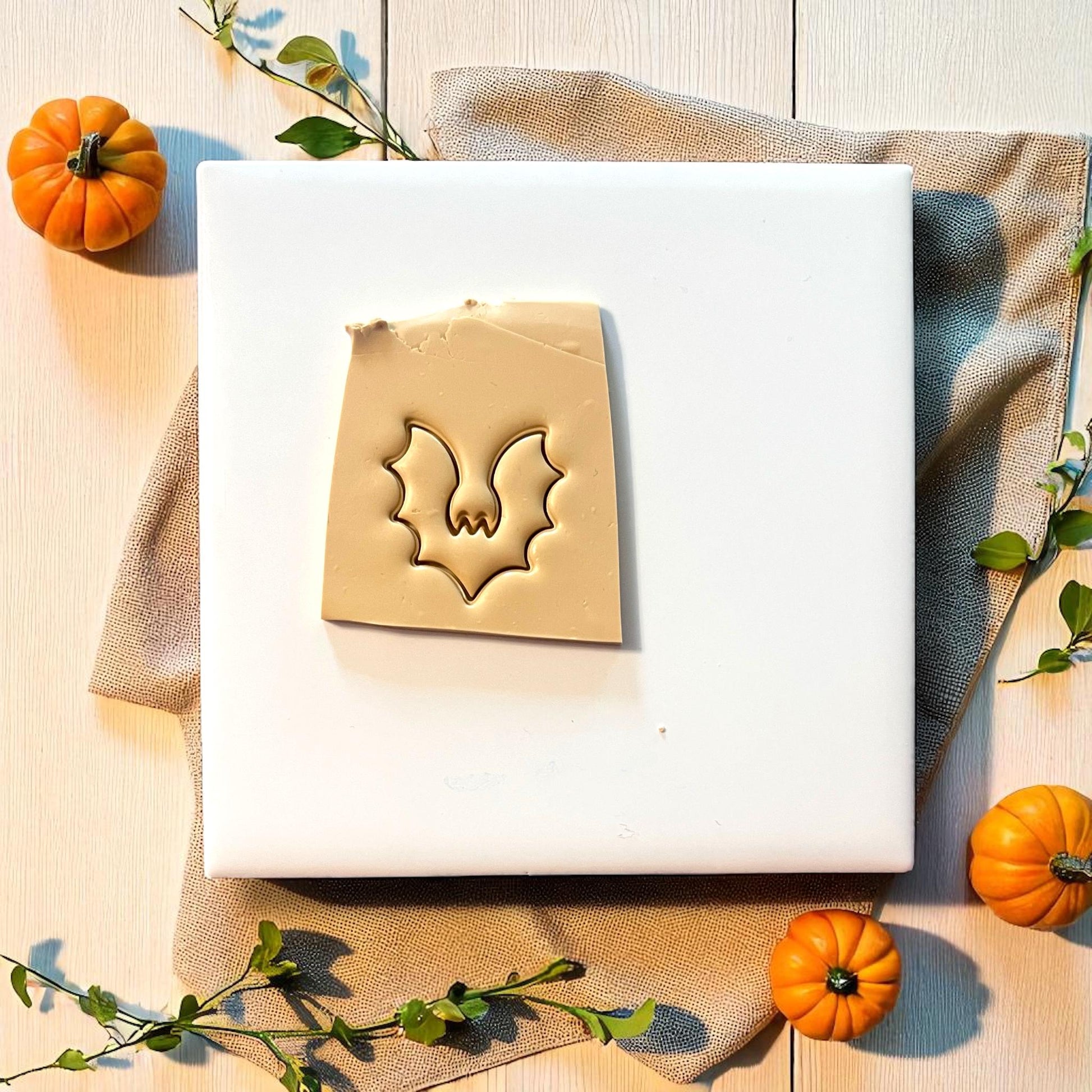 Bat clay imprint pressed into beige clay sheet with pumpkins and greenery