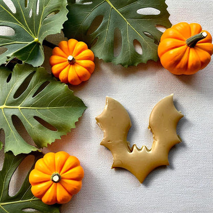 Bat clay imprint with pumpkins and tropical leaves on fabric background